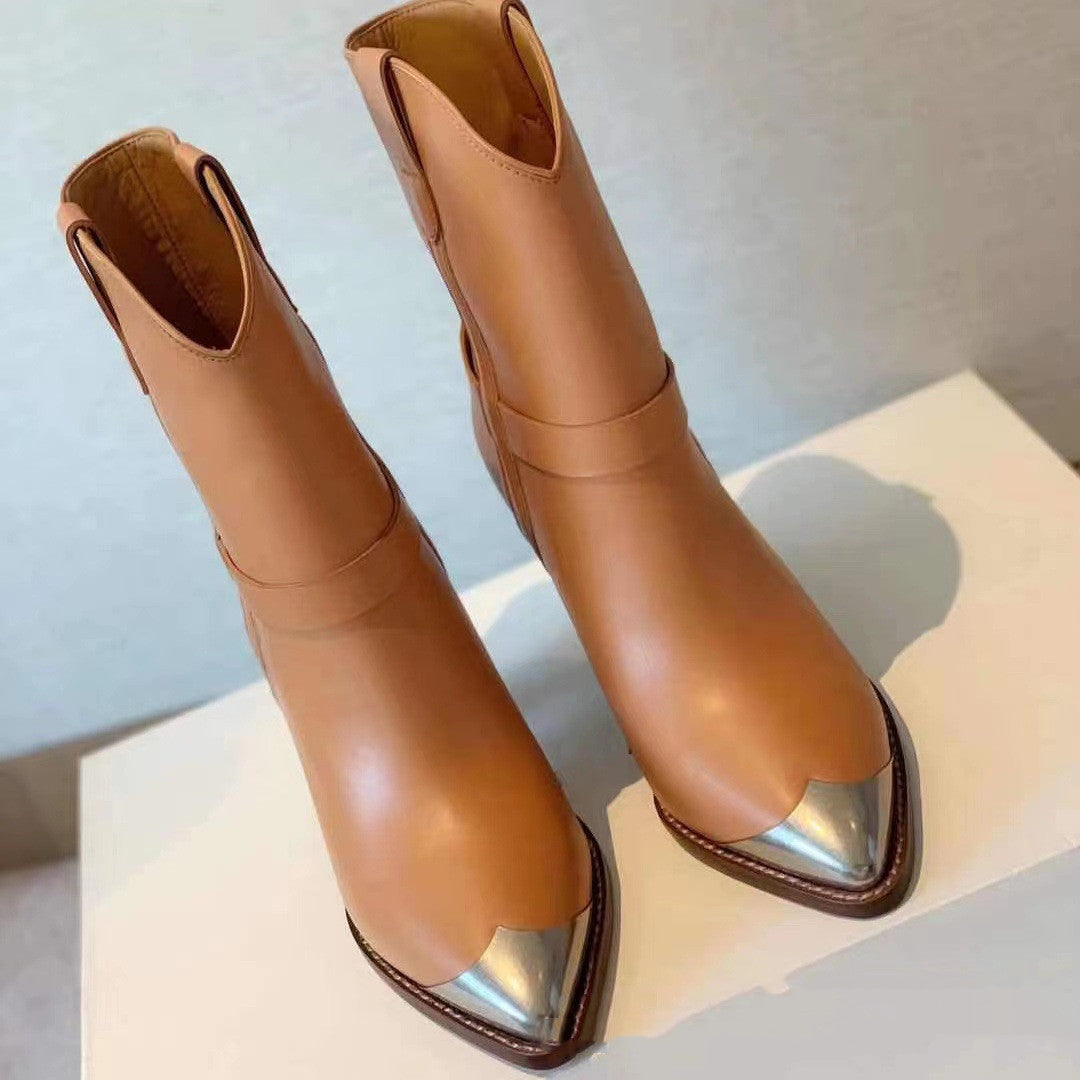 Pair of tan ankle boots with metallic pointed toes on a light background