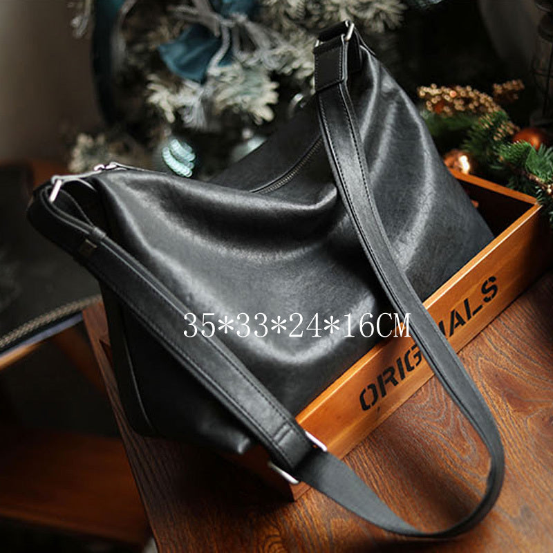 Black leather handbag on a wooden surface with dimensions displayed