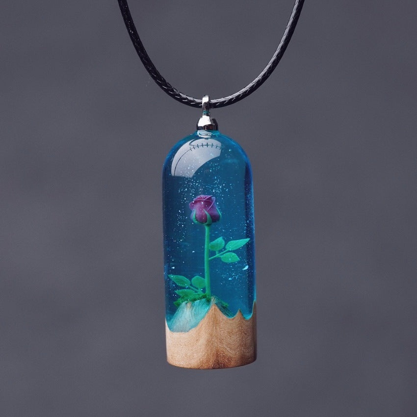 Necklace with a pendant featuring a rose in blue water and wooden base on a dark background