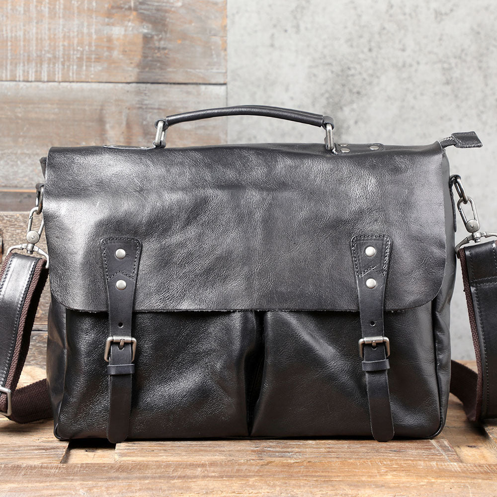 Black leather satchel bag on a wooden surface with a neutral background