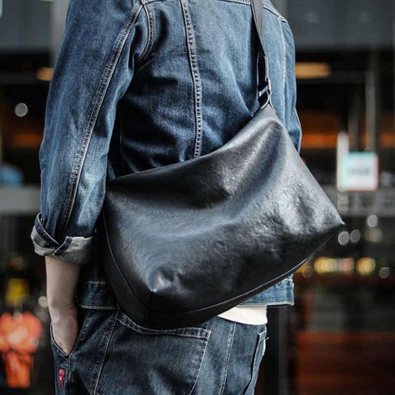 Person wearing a black leather shoulder bag with a blurred background