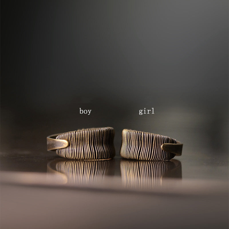 Two bronze bracelets labeled 'boy' and 'girl' on a reflective surface with a dark background.