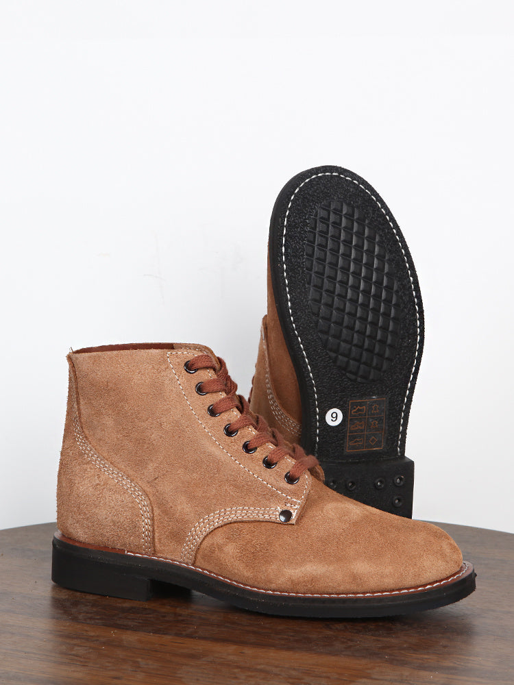 Brown leather boot with black sole on a wooden surface