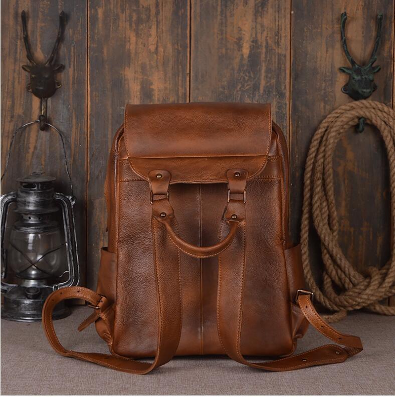 Brown leather backpack on a wooden floor with rustic decor.