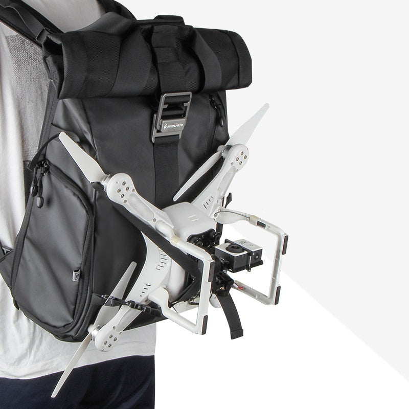 Person wearing a backpack with a folded drone attached on a white background