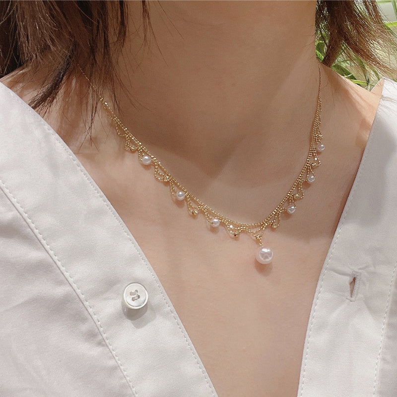 Pearl necklace worn by a person with a white shirt in the background