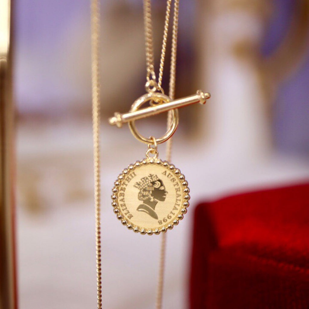 Gold necklace with a round pendant featuring a profiled face on a blurred background
