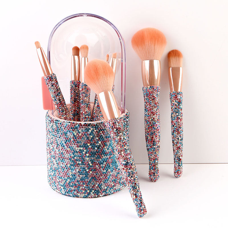 Makeup brushes with colorful handles in a glittery holder on a white background