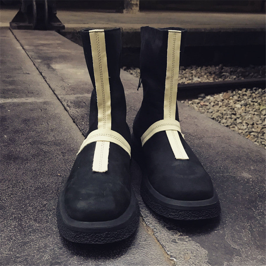 Black boots with white straps on a stone surface