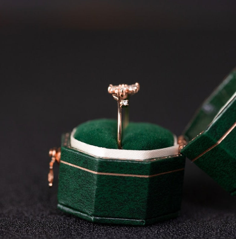 Gold ring in a green jewelry box on a black background