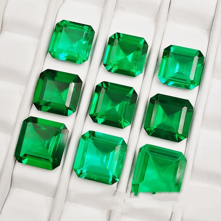 Green gemstones arranged in a grid on a textured white surface