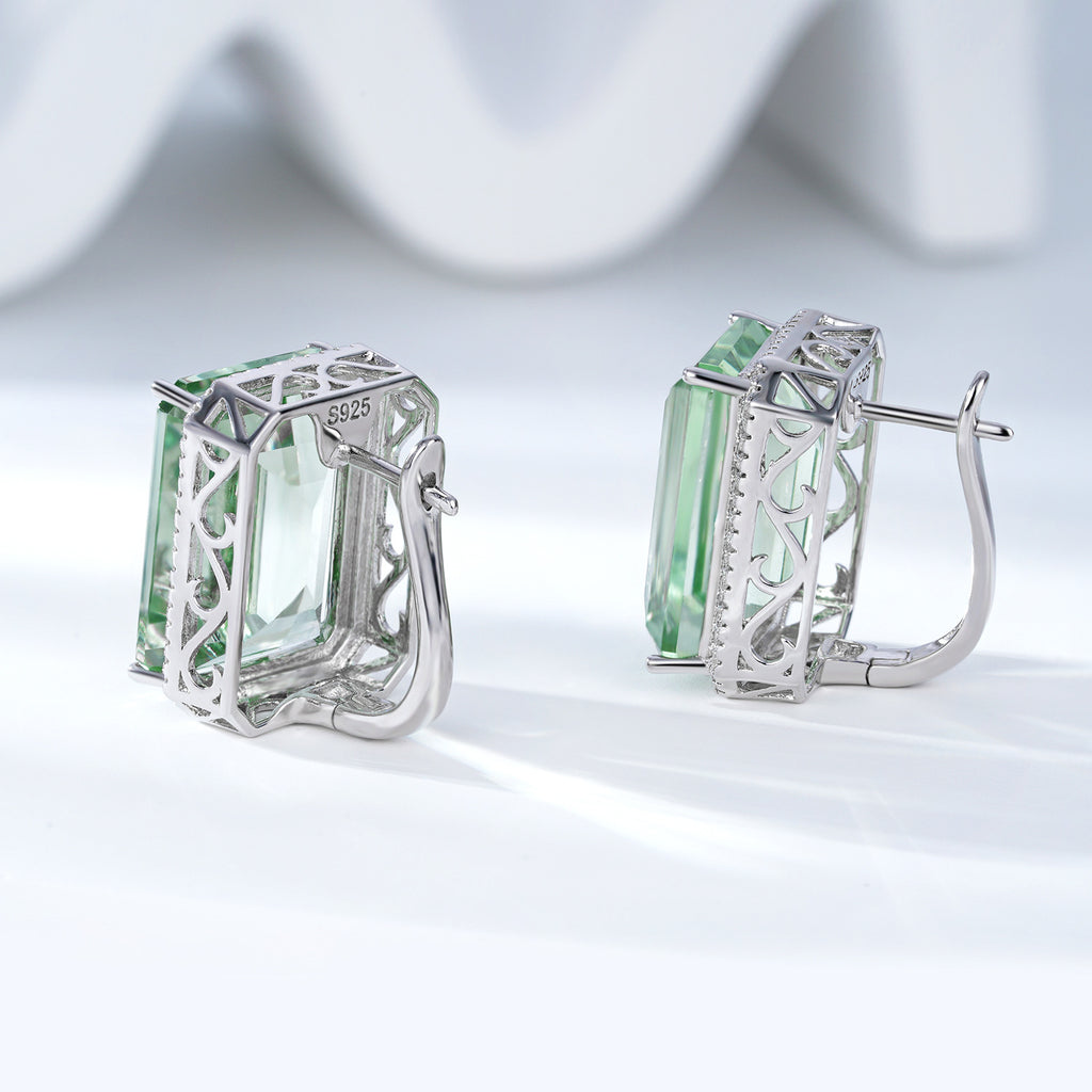Pair of silver hoop earrings with green gemstones on a light background