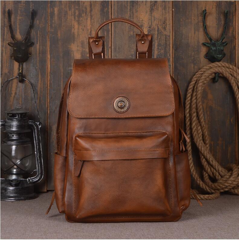 Brown leather backpack with decorative buckle on a wooden background