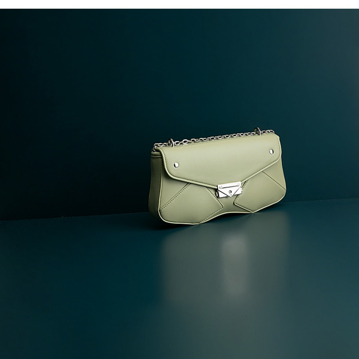 Green handbag with a chain strap on a dark background