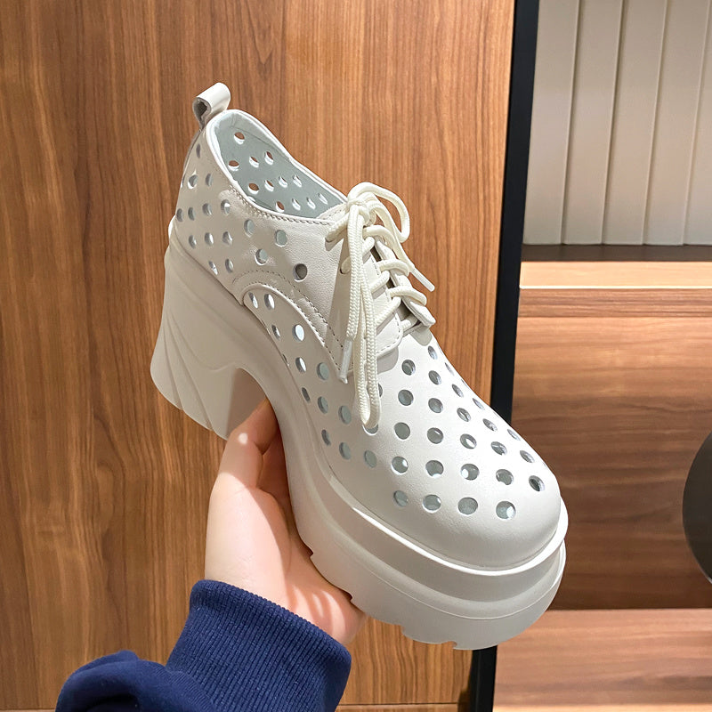 White perforated sneaker held by a person against a wooden background