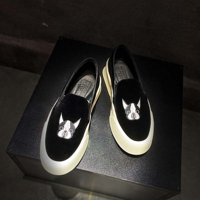 Black loafers with cat face designs on a dark surface