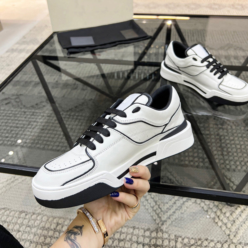 White sneakers with black accents held by a hand on a glass table.