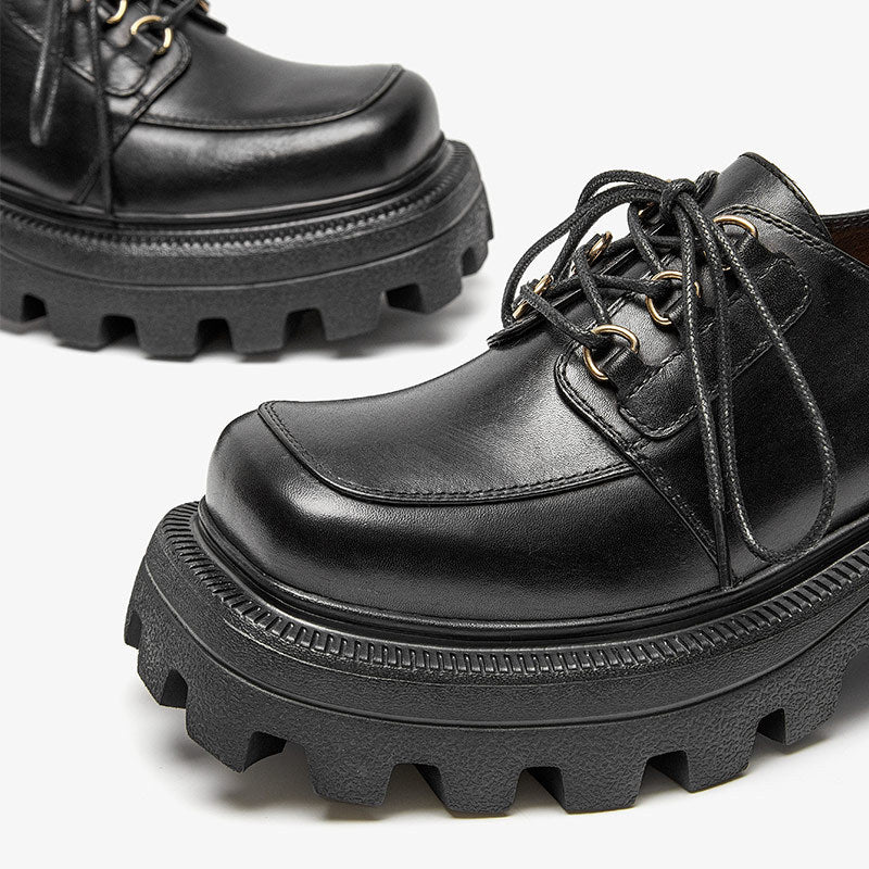 Black leather shoes with thick soles on a light gray background
