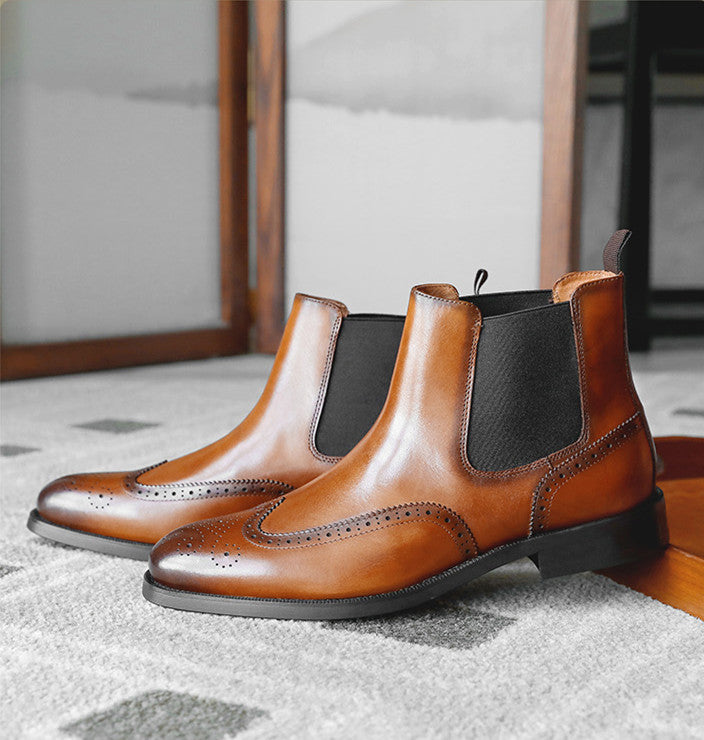 Pair of brown leather Chelsea boots on a textured surface with a neutral background