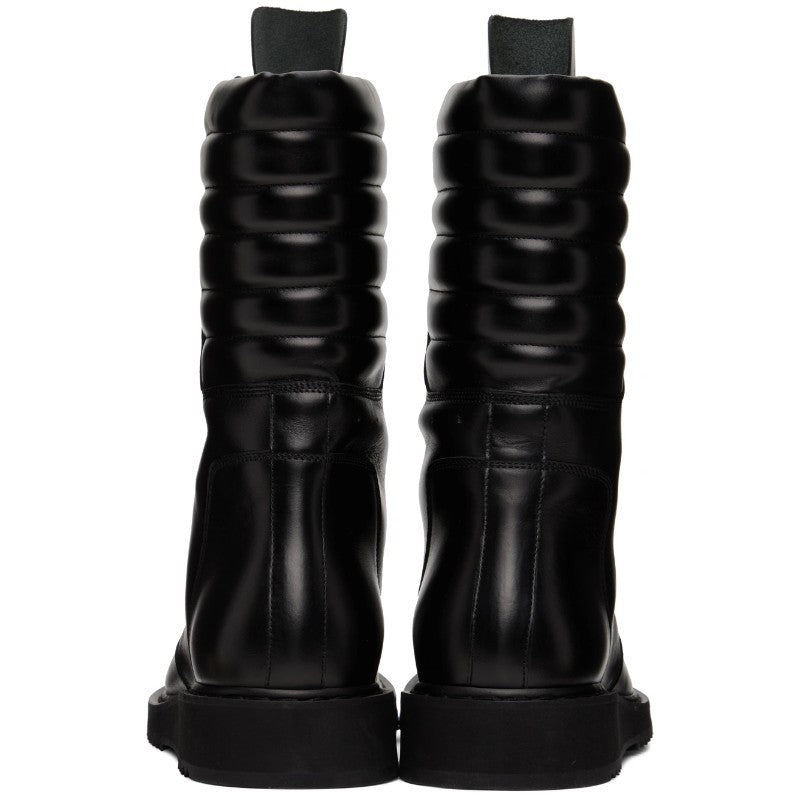 Pair of black riding boots with textured top on a white background